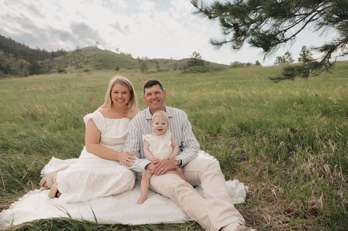The Williams family sitting together in a grassy field with Colorado foothills in the background